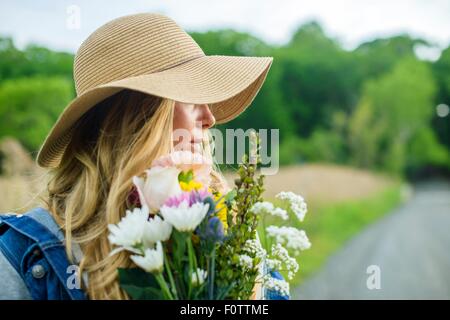 Retrato de mujer joven con ramo de flores y vestido con sombrero de paja