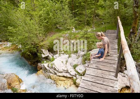 Mujer madura con el hijo sentado en la pasarela de madera, Bovec, soca, Eslovenia