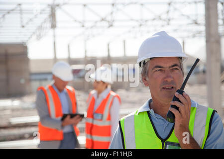 Trabajador hablando por walkie-talkie en sitio en construcción Foto de stock