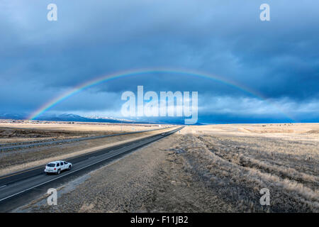 Un alto ángulo de visualización del automóvil a rainbow en remoto camino