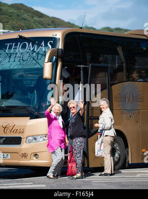 Tres mujeres mayores turistas agitando como entrenador en un autobús que va para un viaje de un día de excursión, viaje UK Foto de stock