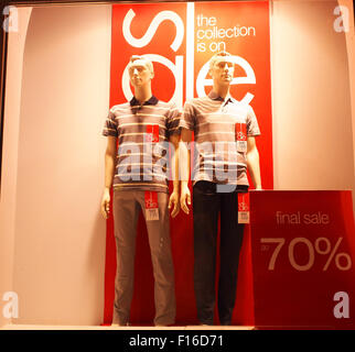 Dos varones de maniquí en una vitrina, vestida con pantalones y camisetas típicas comunes. En el escaparate está escrito - la venta final de 70 Foto de stock