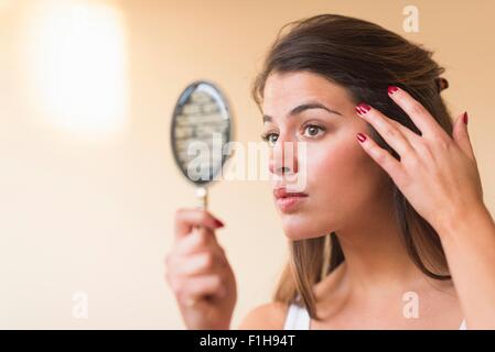 Mujer joven mirando en el espejo de mano