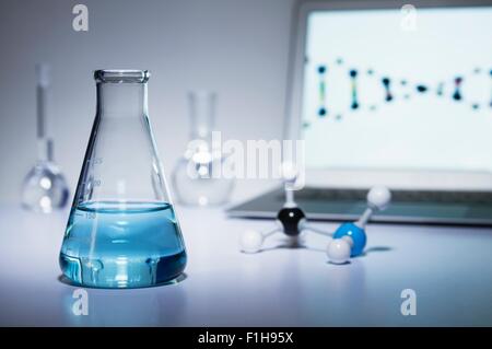 La investigación química. Matraz Erlenmeyer que contiene líquido de color,  una bola-y-stick modelo molecular y ordenador portátil Fotografía de stock  - Alamy