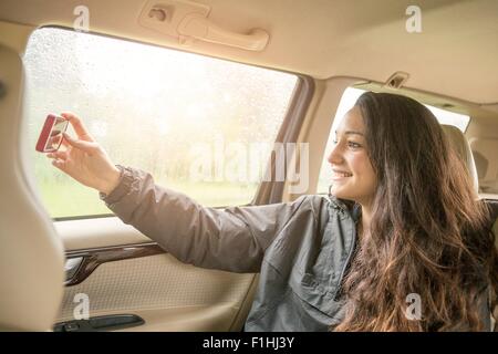 Adolescente tomando selfie smartphone en coche asiento de atrás