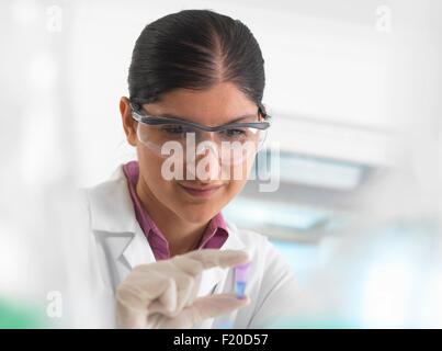 Visualización científico femenino muestra en eppendorf delante de las pruebas de ADN en un laboratorio.