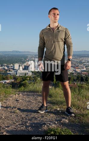 Retrato de macho joven corredor en pista de tierra por encima de la ciudad en el valle Foto de stock