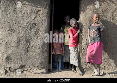 Kenya, reserva de Masai Mara, Masai a niños pequeños a la entrada de sus chozas en un pueblo tradicional Massai Foto de stock