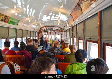 Los pasajeros sentados en los bancos de madera clásica a bordo del famoso tranvía de San Carlos en Nueva Orleans, Luisiana Foto de stock