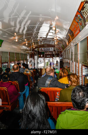 Los pasajeros sentados en los bancos de madera clásica a bordo del famoso tranvía de San Carlos en Nueva Orleans, Luisiana Foto de stock