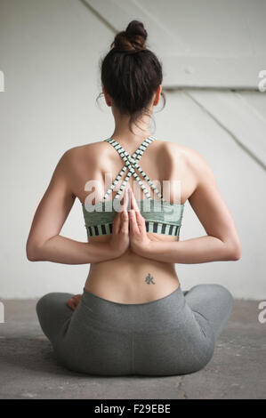 Vista trasera de una mujer adulta media haciendo pashchima namaskarasana posición en yoga studio, Munich, Baviera, Alemania
