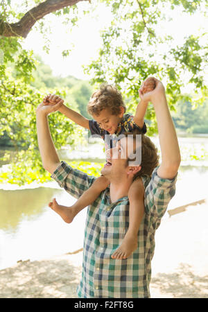 Juguetón hijo padre llevar a hombros en lakeside Foto de stock