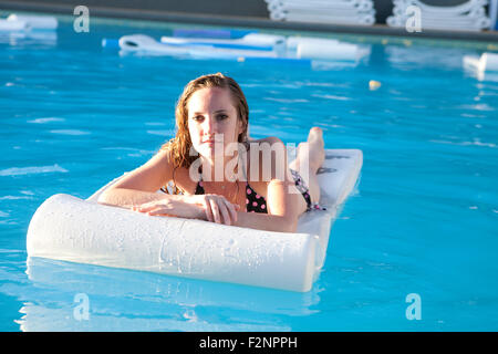 Mujer flotando en balsa en piscina