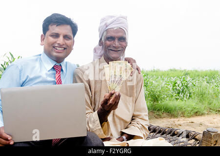 Hombre de negocios rural indio y el campesino granja portátil y dinero mostrando Foto de stock