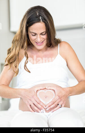 Mujer alegre y con el corazón en el abdomen embarazadas