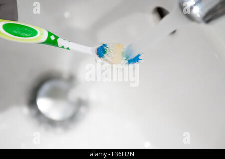 Cepillo de dientes se enjuaga bajo el grifo de agua de un grifo