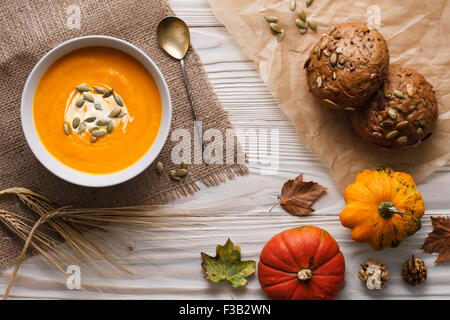 Tradicional sopa de calabaza con semillas y fresco horneado justo centeno prohibiciones sobre un fondo de madera blanca.