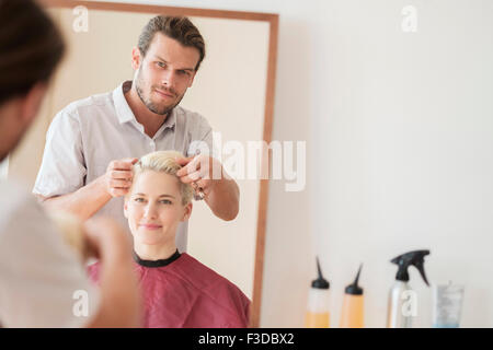 Peluquería peinando el cabello de la mujer Foto de stock