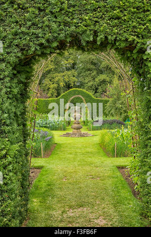 Hermoso jardín inglés vistos a través de un portón con planta trepadora Foto de stock