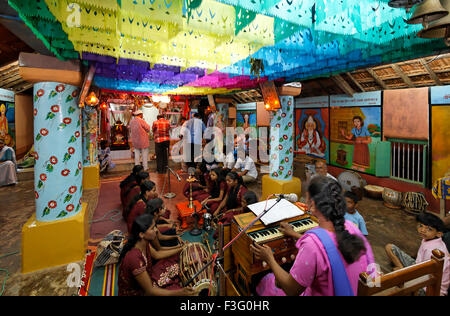 Niñas cantando bhajan tocando instrumentos musicales harmonium tabla en el templo ; India ; asia