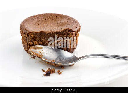 Macro closeup de mitad comido tarta de chocolate muffin con cucharilla sucia Foto de stock