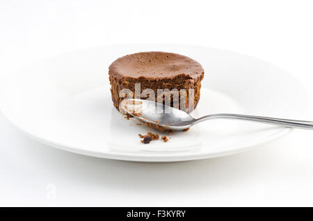 La mitad comido delicioso pastel de chocolate muffin con cucharilla sucia Foto de stock
