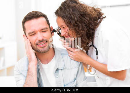 Vista de un atractivo joven doctor comprobación de la oreja del paciente Foto de stock