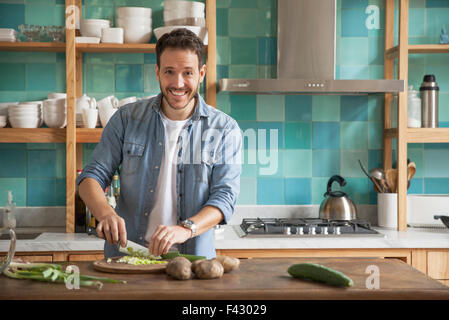 El hombre cortando los ingredientes en la cocina, Retrato Foto de stock