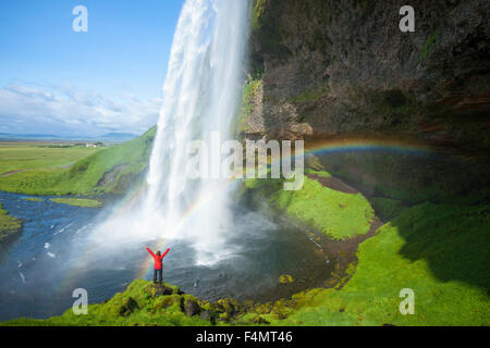 Persona y rainbow debajo de 60m de alto, la cascada Seljalandsfoss Sudhurland, Islandia. Foto de stock