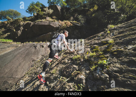 España, Galicia, A Capela, Ultra Trail Runner subiendo una pendiente de roca Foto de stock