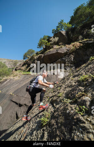 España, Galicia, A Capela, Ultra Trail Runner subiendo una pendiente de roca Foto de stock