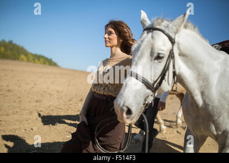 Atractiva chica joven está caminando con su caballo