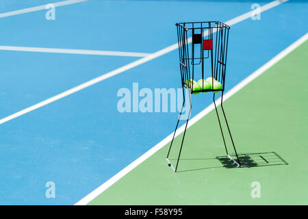 Hermosa cancha de tenis con una cesta de bolas y pelotas de tenis en ella Foto de stock