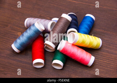 Hilo de coser en diferentes colores sobre la mesa de madera Foto de stock