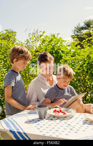 Suecia, Halsingland, Jarvso, imagen de dos hijos (4-5, 6-7) y su madre en el jardín