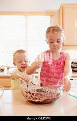 Hermanos derritiendo el chocolate en tazón Foto de stock