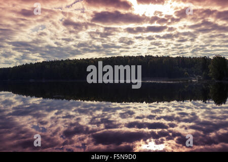 Brillante cielo nublado sobre el lago refleja aún en el agua Foto de stock
