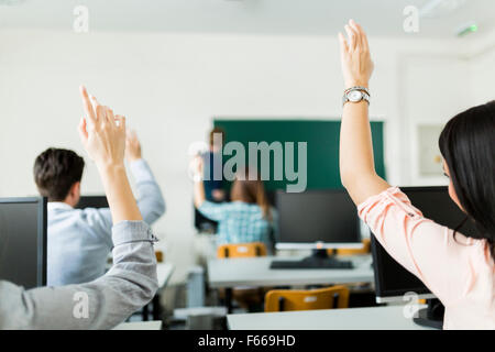 Los jóvenes estudiantes levantando las manos en un aula mostrando están listos