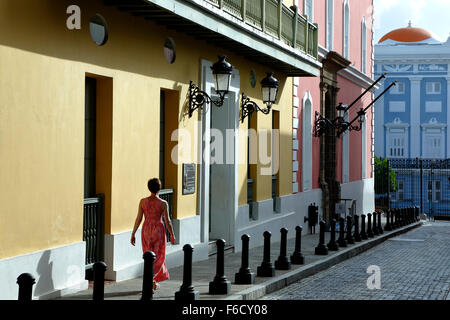 Mujer y coloridas fachadas coloniales españolas (Oficina Estatal de Preservación Histórica), Calle Fortaleza, el Viejo San Juan, Puerto Rico Foto de stock