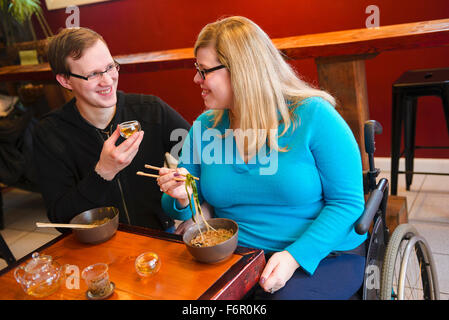 Mujer parapléjicos y novio comiendo fideos en tea shop