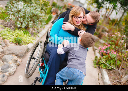Parapléjicos abrazando a la mujer y la familia en el jardín