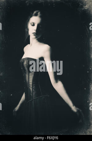 Retro espectacular retrato de una hermosa chica gótica triste entre la oscuridad. Efecto película antigua, en blanco y negro