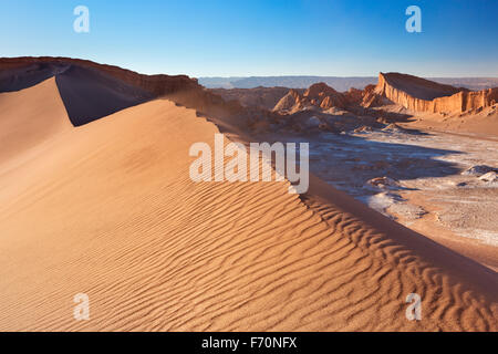 Una alta duna de arena y formaciones rocosas distantes. Fotografiado en el Valle de la Luna en el desierto de Atacama, norte de Chile, en sun Foto de stock