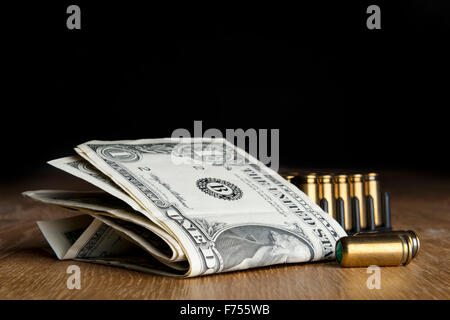 Imagen de los billetes de dólar con pistolas cartuchos en una tabla Foto de stock