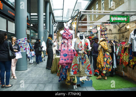 Spitalfields Market, Londres, Inglaterra, Reino Unido. Titular de calado vendiendo coloridos trajes africanos. Foto de stock