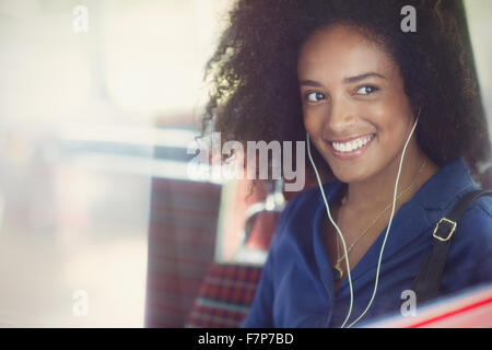Mujer sonriente con afro, escuchar música con auriculares en bus. Foto de stock