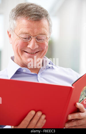 Senior sonriente hombre mirando el Álbum de fotos