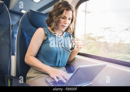 Mitad mujer adulta en el tren, utilizando el portátil