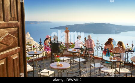 Fira (la capital de Santorini): turistas descansando sobre el griego café restaurante en la terraza, la isla de Santorini, Grecia
