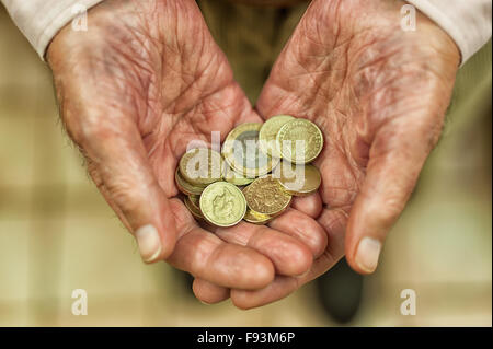 Oro brillante pound coins celebrada en manos mostrando todos los pequeños ahorros y dinero petición de ayuda pobreza pensionista Foto de stock